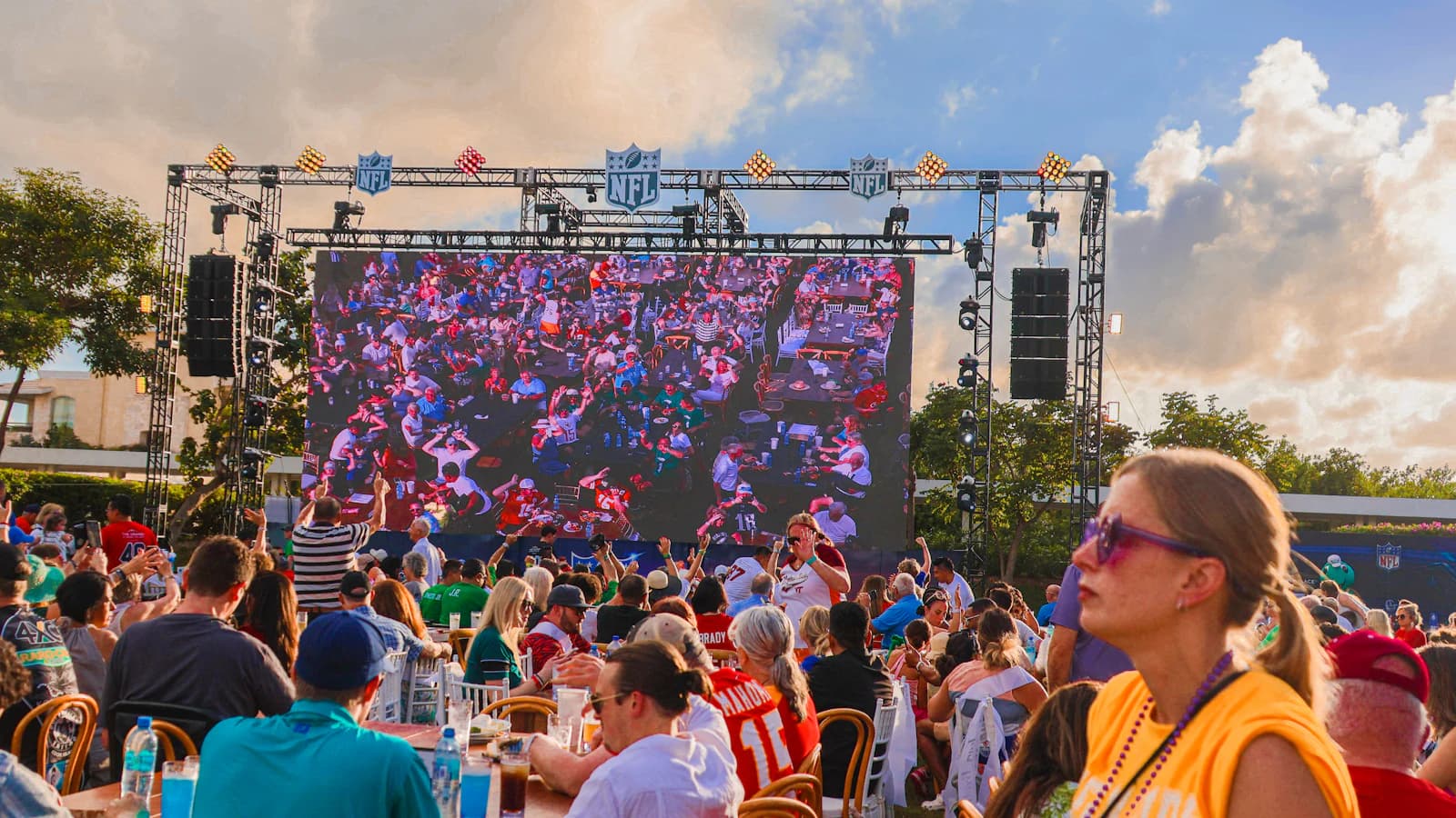 A crowd gathered at tables in front of a big screen for a game