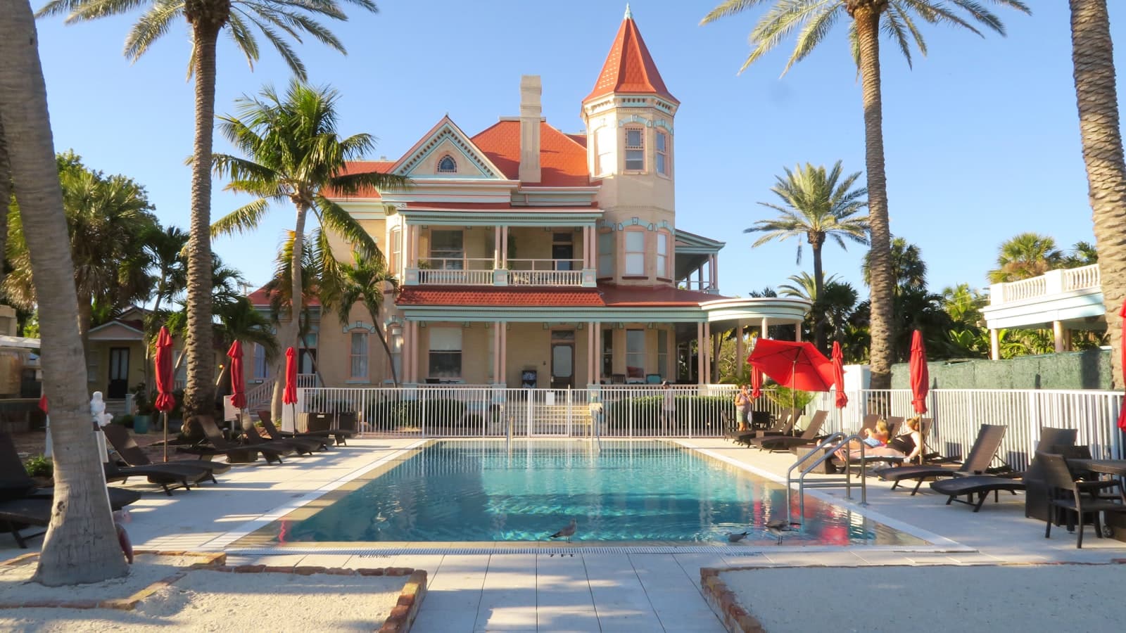 a large house with a swimming pool surrounded by palm trees