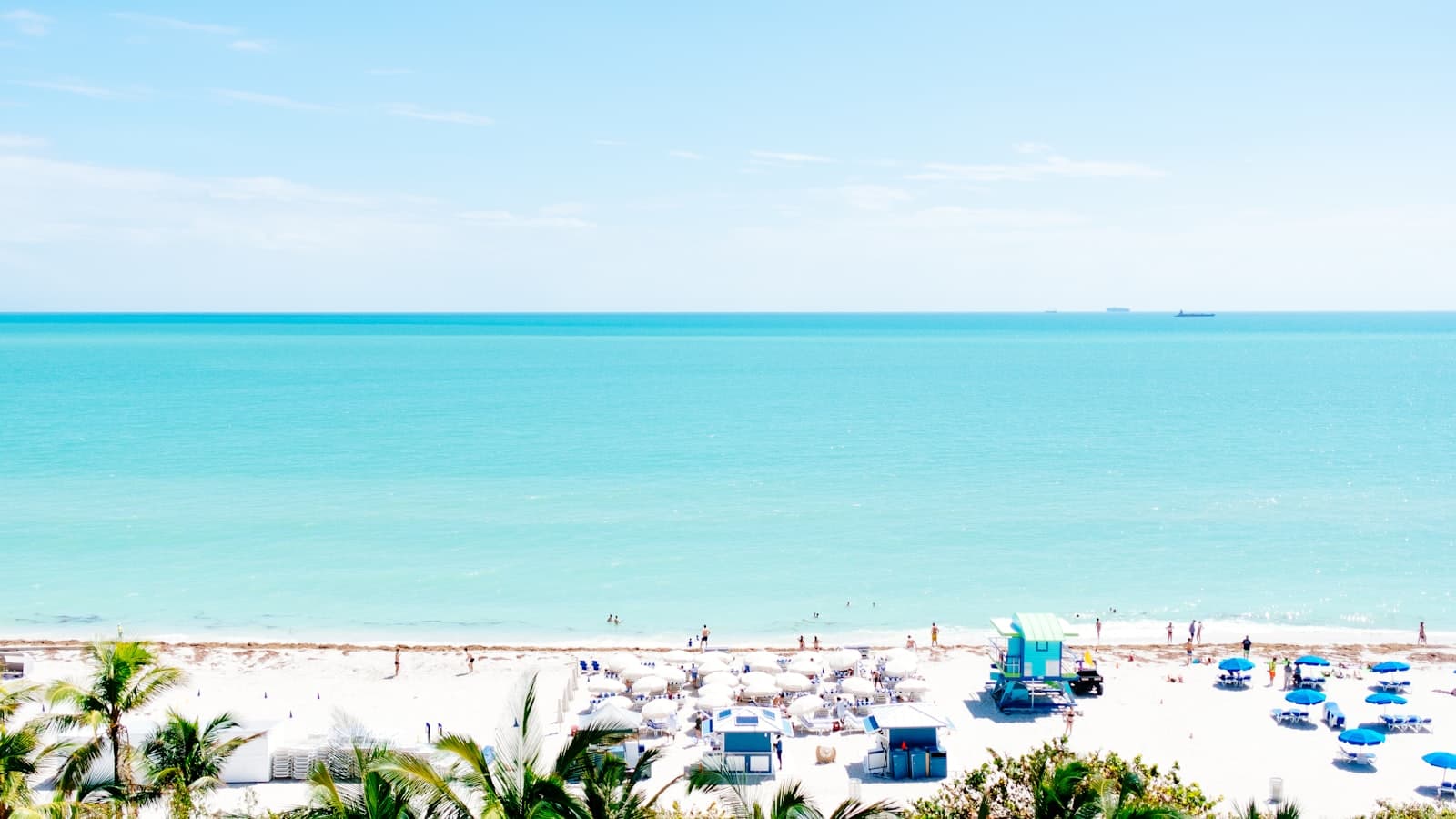 white sand beach with stalls under blue sky