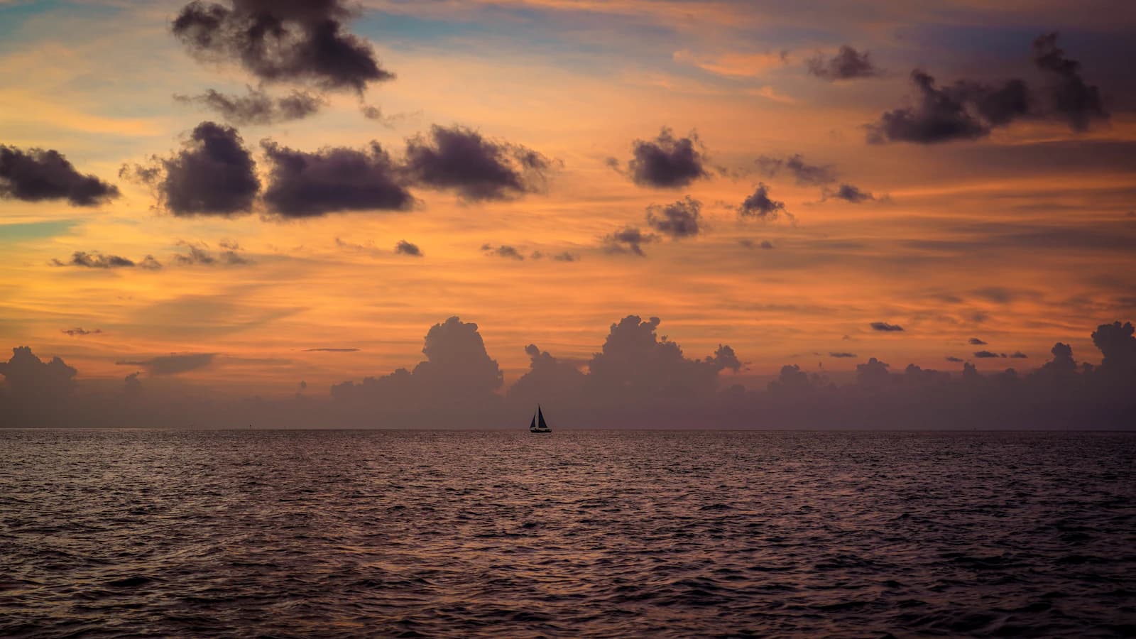 a sailboat in the ocean at sunset