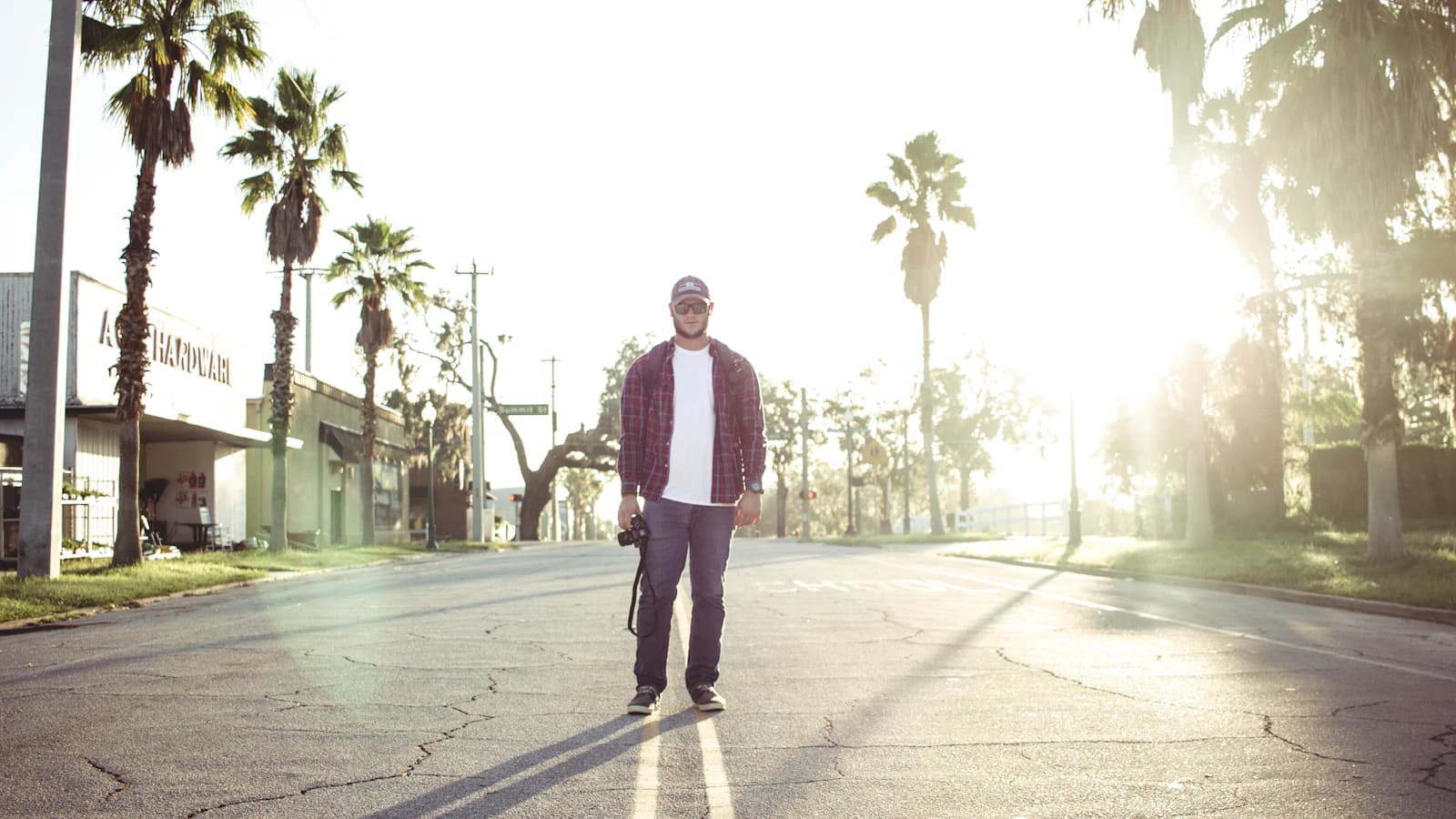 man holding black DSLR camera standing on road during daytime